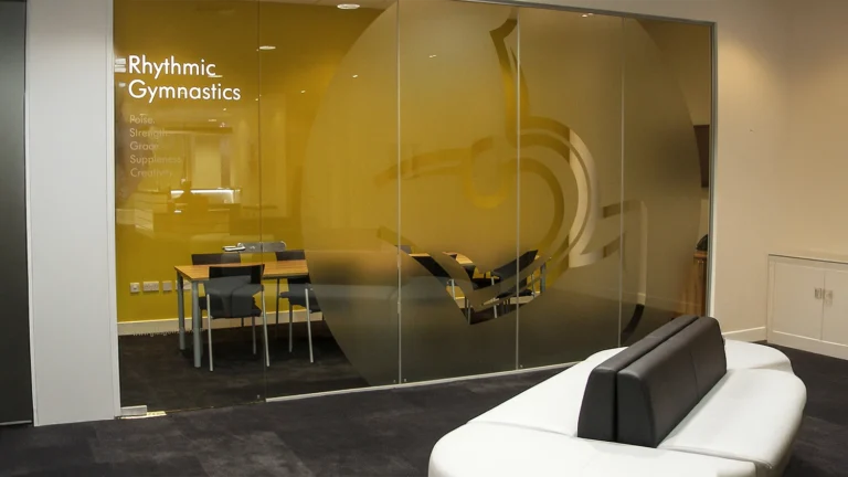 Custom frosted glass window film with branding and a large decorative logo applied to an office glass partition.