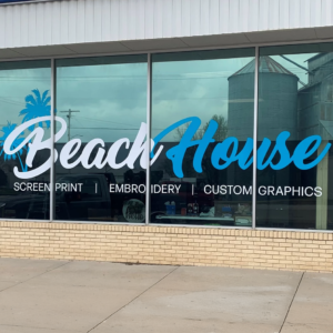 Large custom vinyl lettering on a storefront window displaying "Beach House" with a palm tree graphic.