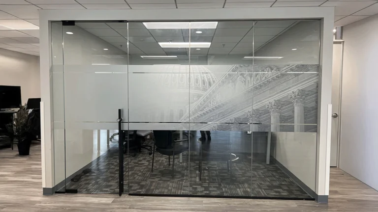 Custom frosted and etched glass window graphics featuring an architectural design on a modern office partition.