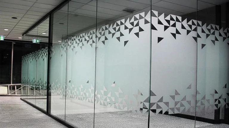 Modern frosted glass window film with a geometric cut-out pattern applied to office glass partitions.