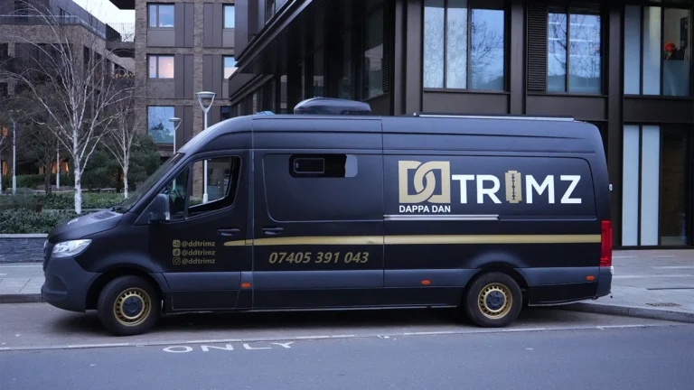 Matte black Mercedes Sprinter van with gold and white branding for "Trimz" parked on a city street.