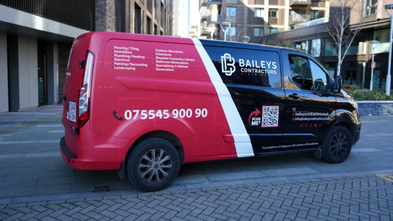 Side view of Baileys Contractors van with a professional red and black vinyl wrap, showcasing company branding, services, contact details, and QR codes, parked in an urban setting.