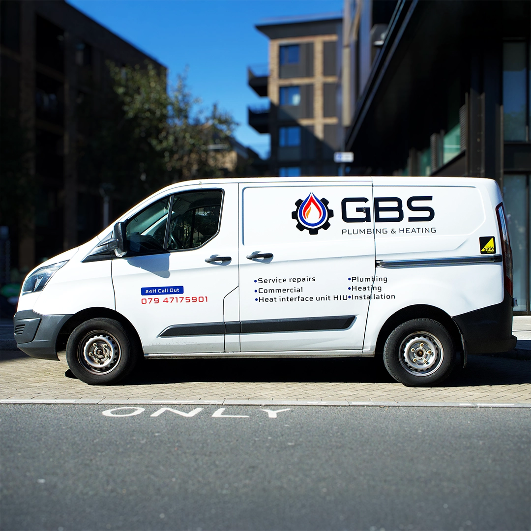 White Ford Transit Custom van with professional GBS Plumbing & Heating vinyl decals and service list, parked on a London street.