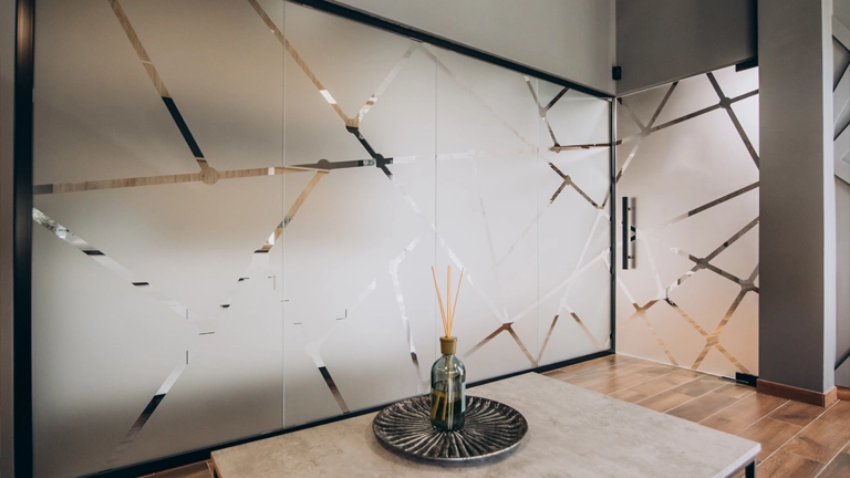 Interior glass office door with a frosted vinyl graphic of an abstract, upward-swooping, wing-like or flame-like logo, partially obscuring the view of the modern office space beyond.