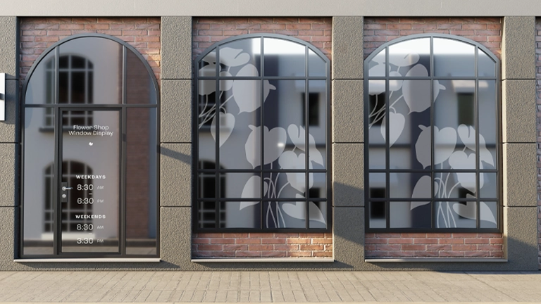 Flower shop storefront featuring three arched windows set in a brick facade. The two large windows display frosted vinyl graphics of stylized tulips or similar large flowers.