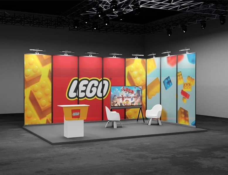 A professional L-shaped exhibition booth for LEGO featuring large-scale backlit graphics, a branded reception podium, and a digital display screen