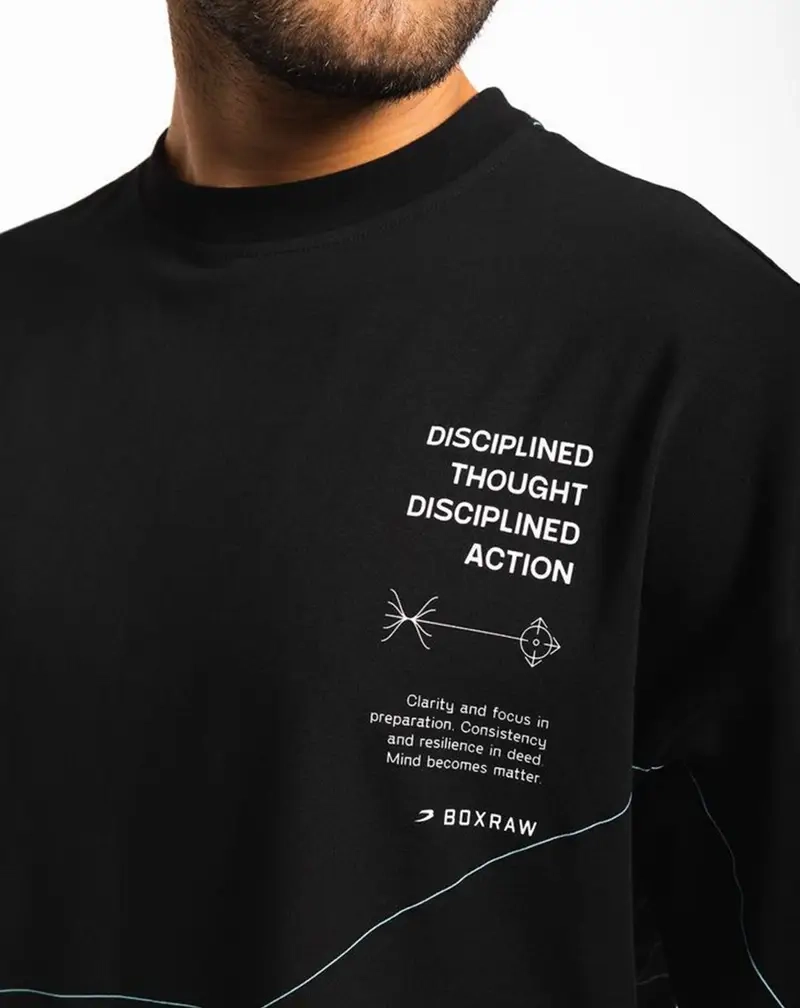 Close-up of a person wearing a black t-shirt featuring white text that reads "DISCIPLINED THOUGHT DISCIPLINED ACTION" alongside technical diagrams and the BOXRAW logo.