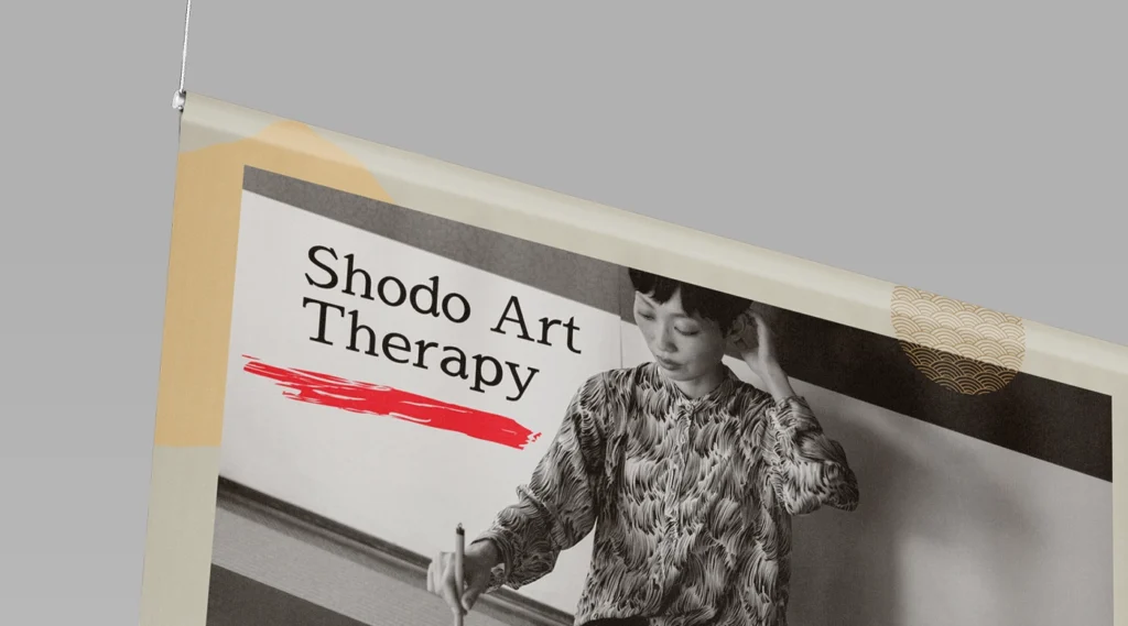 A close-up of a cream and black indoor PVC banner for 'Shodo Art Therapy,' showing a horizontal pole pocket at the top with a thin wire cable for suspension.