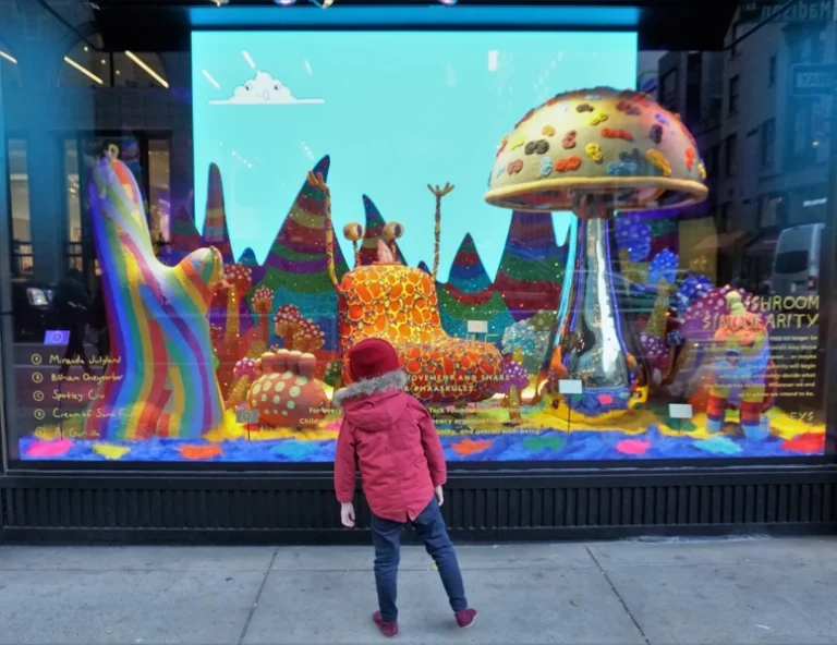 A vibrant retail window display for 'Mushroom Singularity' at Barneys New York, featuring large-scale colorful sculptures and interactive touch-points on the glass.