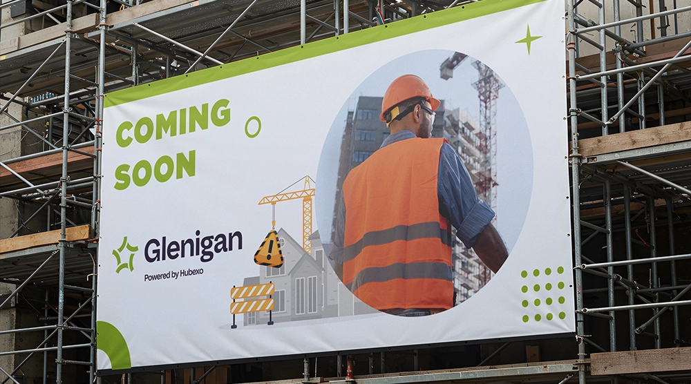 Large "COMING SOON" banner for Glenigan mounted on a multi-story scaffolding structure at a construction site.