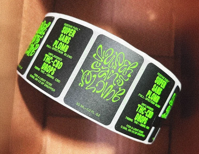 A roll of custom-printed blackproduct label with vibrant neon green typography for "Super Sans Plomb" THC-CBD drops, showing a matte finish and precise rounded corner die-cuts