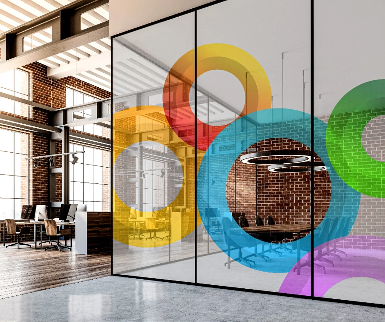 A modern industrial loft office with brick walls and glass partitions featuring large, translucent colorful overlapping circle graphics in yellow, red, blue, and green.