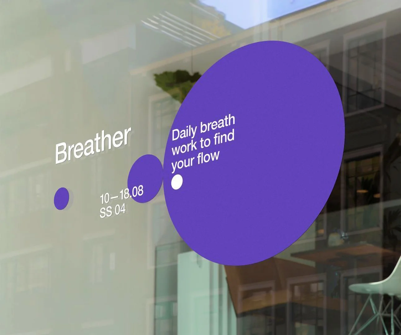 Close-up of a glass window featuring purple circular vinyl decals with the text 'Breather' and 'Daily breath work to find your flow' in white lettering.