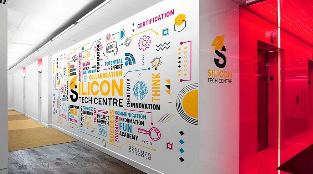 A white office wall featuring a colorful typographic and icon-based mural for 'SILICON TECH CENTRE' next to a bright red glass entryway.