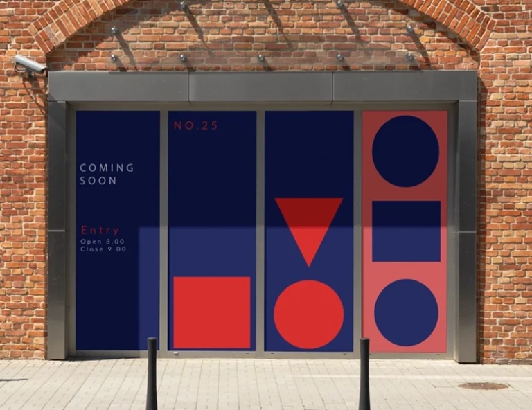 A storefront with large glass windows completely covered by opaque blue and red geometric vinyl graphics, featuring the text 'COMING SOON' and 'NO. 25'