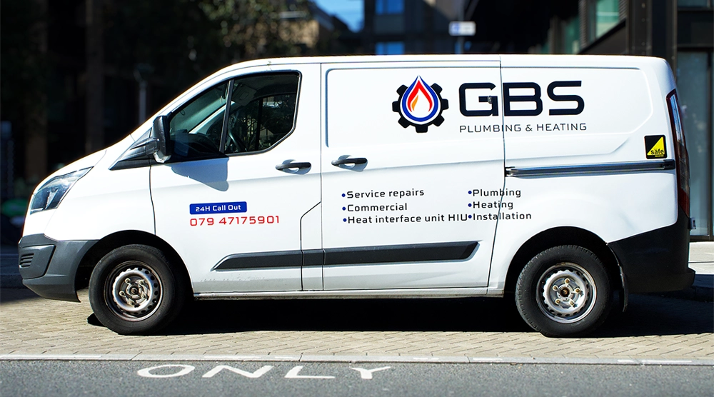 White Ford Transit Custom van with professional GBS Plumbing & Heating vinyl decals and service list, parked on a London street.