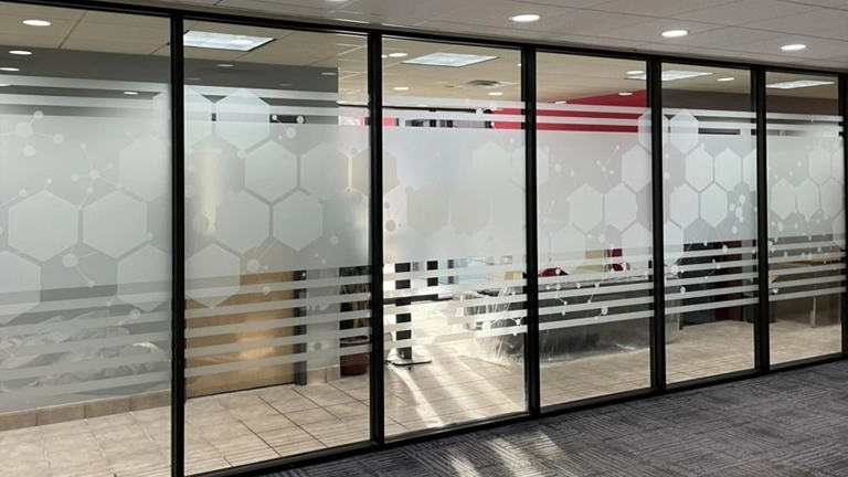 Bold concentric octagon pattern in frosted vinyl on a black-framed glass door.